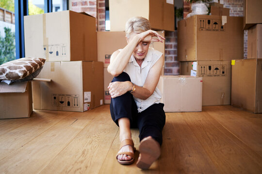 Mature woman, tired and boxes in new home, burnout and exhausted on floor, moving and sad for leaving. Rent, apartment and person in property, rest and thinking of mortgage of house, stress and wood