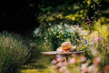 Summer hat and wildflowers on a wooden bench in a vibrant garden