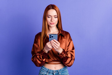 Photo of pretty young woman use smart phone empty space wear brown shirt isolated on violet color...