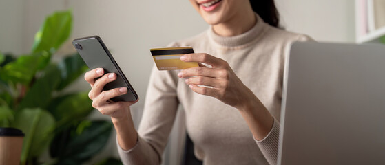 Asian female holding smartphone and credit card, using mobile banking app or online shopping app