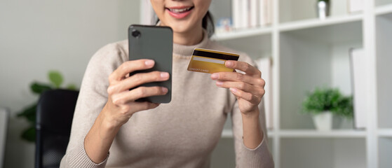 Asian female holding smartphone and credit card, using mobile banking app or online shopping app