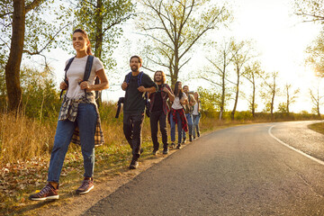 Fototapeta premium Group of friends tourists trekking with backpacks walking in the forest. People men and women on a hiking trip holiday in nature standing in a row. Adventure, travel and tourism concept.