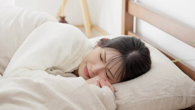 布団の中で寒気を感じる女性