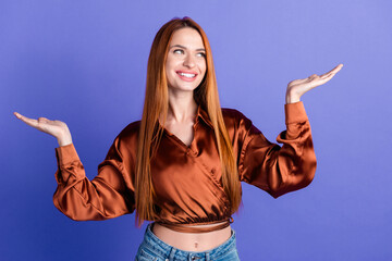 Naklejka premium Photo of pretty young woman look arms hold empty space wear brown shirt isolated on violet color background