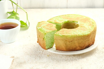 Homemade Pandan Round Sponge Cake or Pandan Chiffon Cake on White Plate so soft and Fluffy on White Table. Homemade Bakery Concept