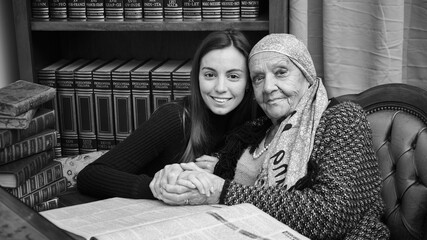 Foto scattata ad una nonna con sua nipote mentre leggono una raccolta di libri antichi.