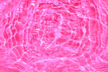 Pink water with ripples. Pink watery background with a dark natural surface and a unique watery...