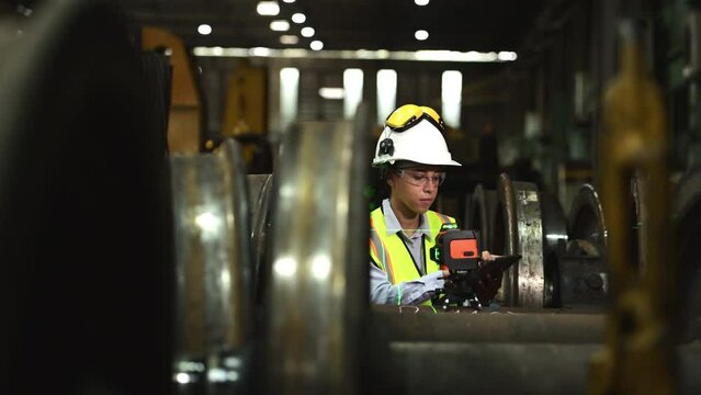 Railway technician in uniform and helmet inspect the train wheels removed from the locomotives in the train workshop.	
