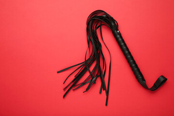 Leather bdsm whip on red background. Erotic toys for BDSM
