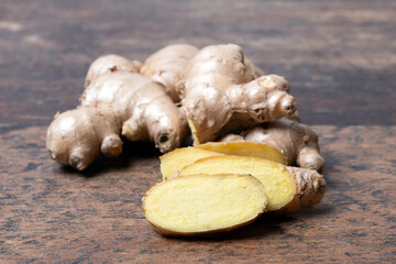 Fresh ginger root with cut slices on wooden background