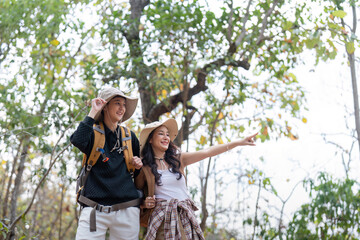 Cheerful romantic lesbian couple traveler with backpack on their backs go hiking through the forest in the mountains in summer