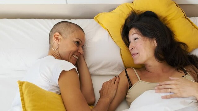 pregnant woman and her lesbian couple smiling relaxed on the bed in the morning