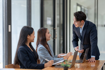 Group of young Asian business people brainstorming, looking at laptop computer.
