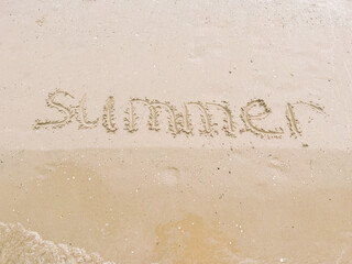 the word summer is written in letters on a sandy beach by the sea