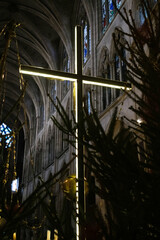 A modern cross with LEDs illuminates the interior of a dark European church.