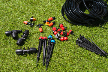 Various garden tools scattered across green grass in the sunlight.