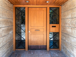 A contemporary design house entrance with a wood and glass door between stonewalls.Travel to...