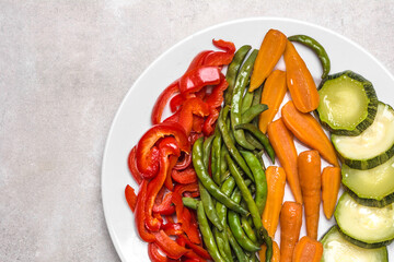 White plate of fresh steamed vegetables, top view. Low calorie diet concept.