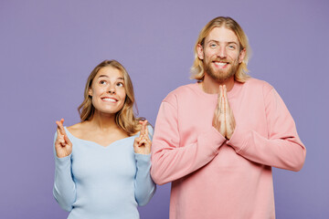 Young couple two friends family man woman wear pink blue casual clothes together hold hands folded in prayer gesture, begging about something isolated on pastel plain light purple background studio.
