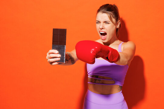 Young fitness trainer sporty woman sportsman wear purple top clothes boxing gloves do selfie shot on mobile cell phone in home gym isolated on plain orange background. Workout sport fit abs concept. - Powered by Adobe
