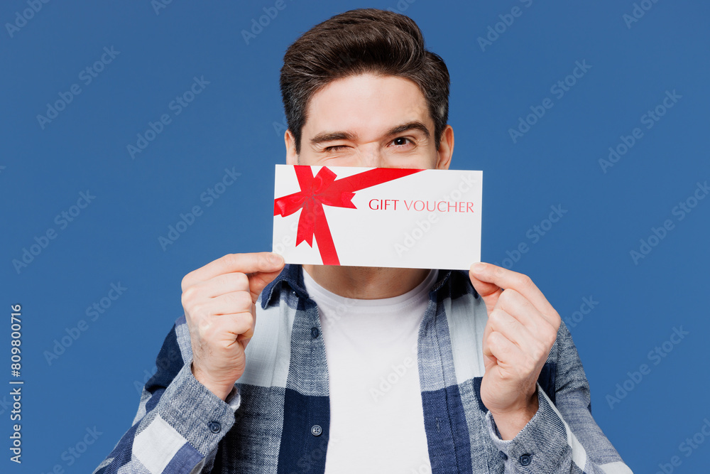 Poster Young happy man wear shirt white t-shirt casual clothes hold cover mouth with gift certificate coupon voucher card for store isolated on plain blue cyan background studio portrait. Lifestyle concept.