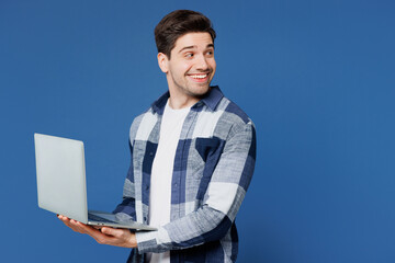 Side view young fun IT man wears shirt white t-shirt casual clothes hold use work on laptop pc computer browsing internet look aside on area isolated on plain blue cyan background. Lifestyle concept.