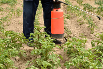 A man holds in his hands a container, a container for a solution and a sprayer, with the help of which the man destroys harmful insects in the garden.