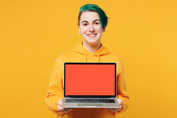 Naklejka premium Young happy IT woman with dyed green hair wear hoody casual clothes hold use work on blank screen workspace area laptop pc computer isolated on plain yellow orange background studio Lifestyle concept