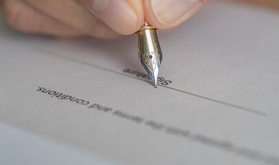 Hand in close up holding a fountain pen signing a document. Signature with fountain pen 