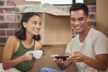 Couple, smartphone and boxes in new house and happy, relax and browse in real estate for mortgage...