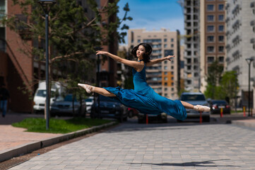 Beautiful Asian ballerina dancing outdoors. Urban landscape. Grand jete. 