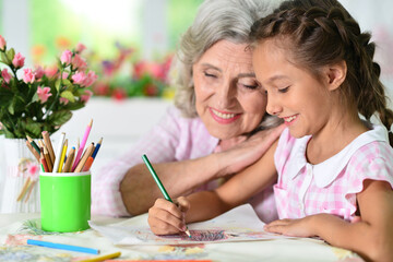 Portrait of a cute little girl drawing with her grandmother