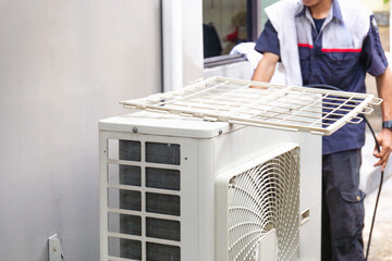 Selective focus of Air conditioner compressor with blurred technician man cleaning air conditioner...