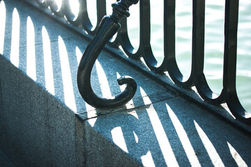High contrast silhouette of wrought iron black fence on a concrete parapet on a shore. Patterns and...
