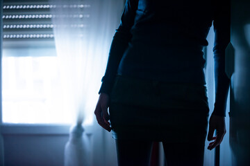 Bluish backlit image of a woman leaning on the wall