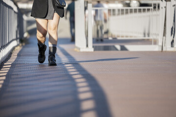 Woman's legs in seven-league boots taking a walk on a metal surface of an elevated walkway