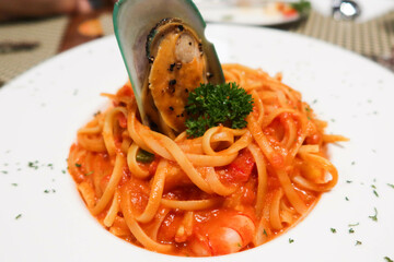 close up of tomato sauce seafood spaghetti with mussel and prawns on a white plate taken in a...