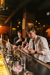 Young guy gets tired of friends and turns on mobile phone in noisy club. Guy retires at bar counter...
