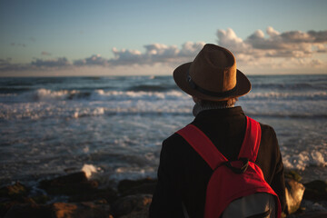 Gentle breeze accompanies man's seaside stroll at dusk.