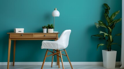 Home workplace with wooden drawer writing desk and white fabric chair near turquoise wall with copy space. Interior design of modern scandinavian home office