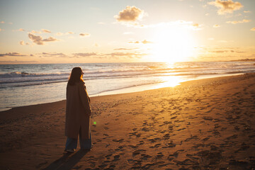 Woman enjoys evening walk by sea.