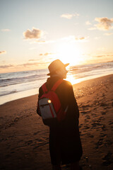 Tranquil scene man walks beach, sun dipping on horizon.