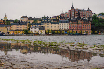 Obraz premium Close up of puddle on the ground with a river and cityscape in the background