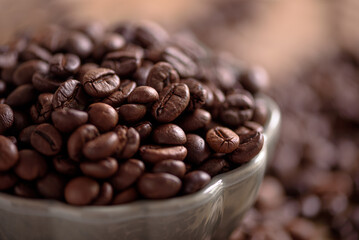 Coffee beans into bowl on white table. Top view. Soft focus - 809834764