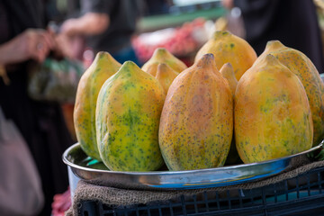 A close-up view captures ripe papayas displayed on a tray, enticingly arranged for sale in a...