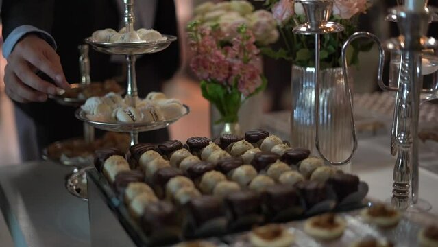 several people tasting desserts at a wedding sweets table