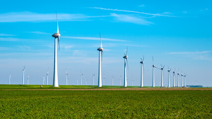 A serene green field is adorned with a row of sleek windmills, their blades gracefully turning in...