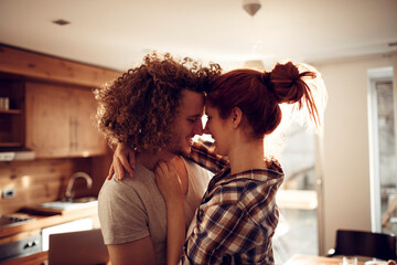 Happy couple embracing and kissing in sunny kitchen