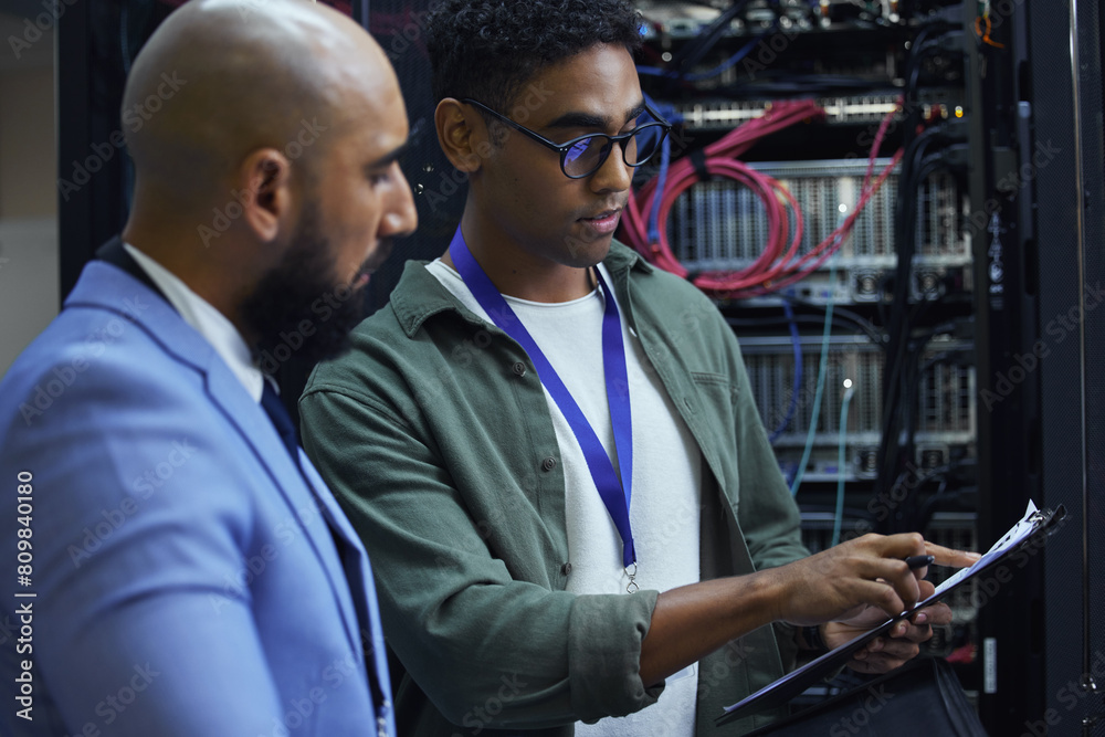 Poster People, clipboard and technician engineer in server room, employees and programmers with paperwork. Men, colleagues and support for machine maintenance, processor hardware and teamwork for system