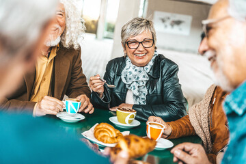 Happy senior people having breakfast sitting at cafe bar - Group of older friends having lunch in...